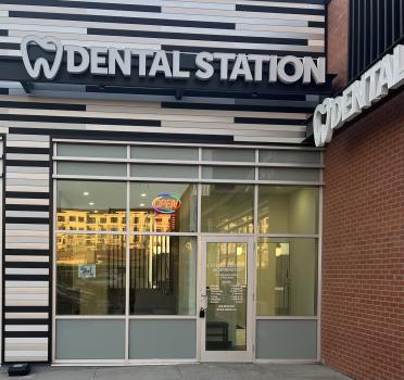 Dental Station storefront with a striped black-and-white exterior, glass doors, and an open sign in the window.