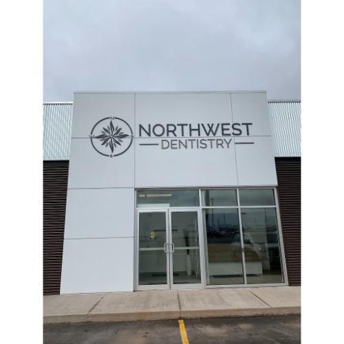 Front entrance of Northwest Dentistry clinic; glass double doors, large sign reading 'NORTHWEST DENTISTRY' with a circular logo on the left.