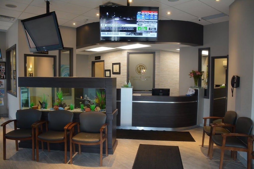 Dental clinic reception with a curved dark front desk, a fish-tank divider, and waiting chairs.