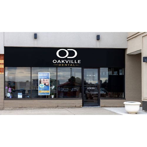 Oakville Dental storefront with a black sign, large front windows showing posters, a glass door, and a white planter on the right.